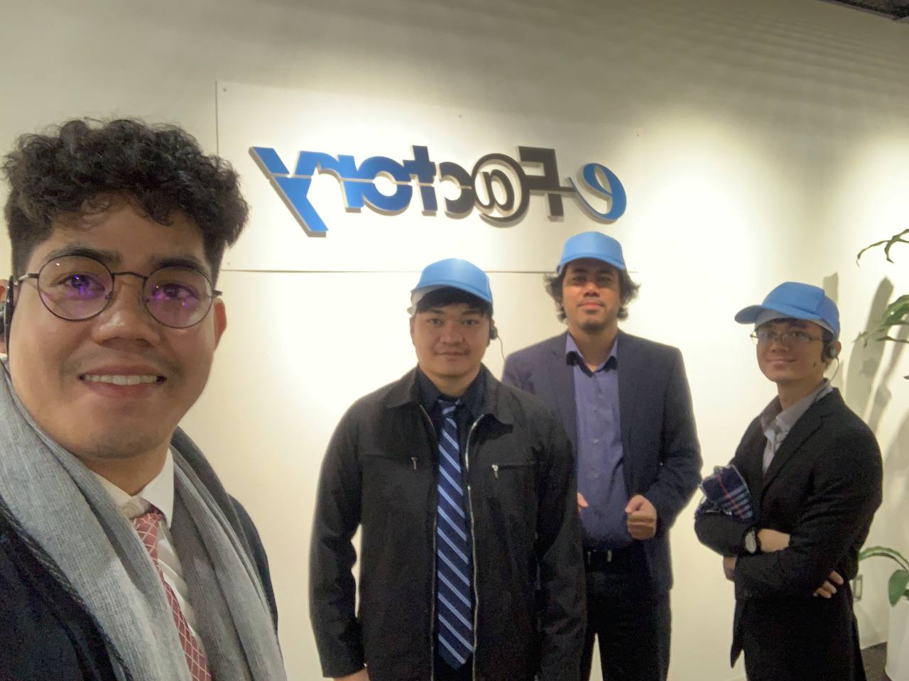 Group photo during the Japan industry visit, in front of an e-F@ctory sign
